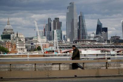  A man walks on Waterloo Bridge to cross the River Thames, backdropped by the skyscrapers and office buildings of the City of London, on May 13, 2020, as people start to return to work after COVID-19 lockdown restrictions were eased. - Britains economy shrank two percent in the first three months of the year, rocked by the fallout from the coronavirus pandemic, official data showed Wednesday, with analysts predicting even worse to come. Prime Minister Boris Johnson began this week to relax some of lockdown measures in order to help the economy, despite the rising death toll, but he has also stressed that great caution is needed. (Photo by Tolga AKMEN / AFP)Editoria: HTHLocal: LondonIndexador: TOLGA AKMENSecao: diseaseFonte: AFPFotógrafo: STR<!-- NICAID(14499072) -->