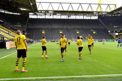 Dortmunds Norwegian forward Erling Braut Haaland (L) celebrates with team players after scoring the opening goal during the German first division Bundesliga football match BVB Borussia Dortmund v Schalke 04 on May 16, 2020 in Dortmund, western Germany as the season resumed following a two-month absence due to the novel coronavirus COVID-19 pandemic. (Photo by Martin Meissner / POOL / AFP) / DFL REGULATIONS PROHIBIT ANY USE OF PHOTOGRAPHS AS IMAGE SEQUENCES AND/OR QUASI-VIDEO<!-- NICAID(14501646) -->