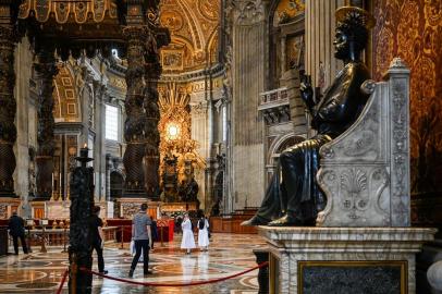 A general view shows St. Peters Baldachin (L) and St. Peters statue (R) while people and nuns visit St. Peters Basilica as it reopens on May 18, 2020 in The Vatican during the lockdown aimed at curbing the spread of the COVID-19 infection, caused by the novel coronavirus. - Saint Peters Basilica throws its doors open to visitors on May 18, 2020, marking a relative return to normality at the Vatican and beyond in Italy, where most business activity is set to resume. (Photo by Vincenzo PINTO / AFP)<!-- NICAID(14502110) -->