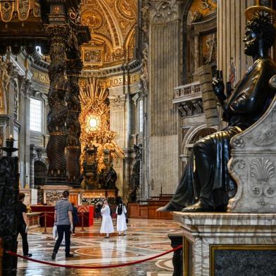 A general view shows St. Peters Baldachin (L) and St. Peters statue (R) while people and nuns visit St. Peters Basilica as it reopens on May 18, 2020 in The Vatican during the lockdown aimed at curbing the spread of the COVID-19 infection, caused by the novel coronavirus. - Saint Peters Basilica throws its doors open to visitors on May 18, 2020, marking a relative return to normality at the Vatican and beyond in Italy, where most business activity is set to resume. (Photo by Vincenzo PINTO / AFP)<!-- NICAID(14502110) -->