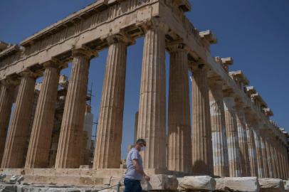 A man wearing a mask walks next to the Parthenon temple on the archeological site of the Acropolis in Athens on May 18, 2020 amid the pandemic of the novel coronavirus (COVID-19). - Greece reopened the Acropolis in Athens and all open-air archaeological sites in the country to the public on May 11 after a two-month closure due to the coronavirus pandemic. (Photo by Aris MESSINIS / AFP)<!-- NICAID(14502109) -->