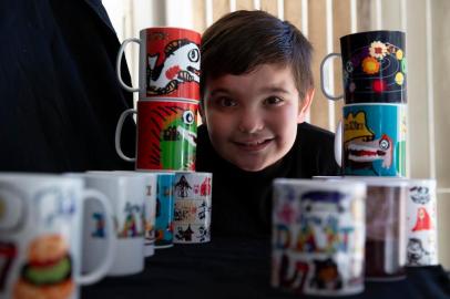  ESTEIO, RS, BRASIL - Daniel Munhos Dias, 06 (autista), faz desenhos inspirados em coisas que ele gosta, desde programas na TV até comida que ele come. Seu pai Caio Dias (músico), e sua mãe Oneida Munhos incentivam o menino. O pai edita os desenhos no computador e faz a arte das canecas pra venda. Isso tem ajudado no orçamento da casa após a parada pela Pandemia, pois a única renda era do pai músico, que está parado. (Foto: Jefferson Botega/Agencia RBS)Indexador: Jeff Botega<!-- NICAID(14501258) -->