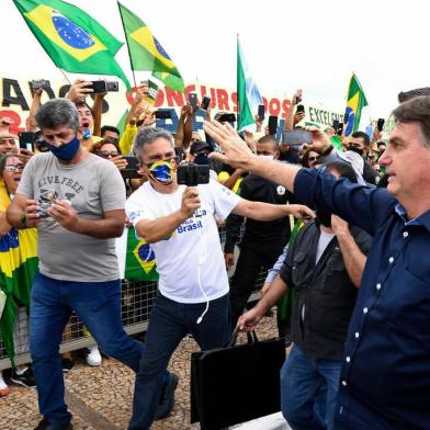 Brazils President Jair Bolsonaro greets supporters upon arrival at Planalto Palace in Brasilia, on May 24, 2020, amid the COVID-19 coronavirus pandemic. - Despite positive signs elsewhere, the disease continued its surge in large parts of South America, with the death toll in Brazil passing 22,000 and infections topping 347,000, the worlds second-highest caseload. (Photo by EVARISTO SA / AFP)<!-- NICAID(14506800) -->