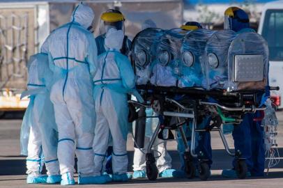 Health workers move a COVID-19 infected patient to a C-130 Hercules, to be taken to the city of Concepcion, at a Chilean Air Force base in Santiago, Chile, on May 24, 2020. - Patients infected with COVID-19 are taken to other cities in the country in order to free up space in the intensive care units of hospitals in Santiago. (Photo by Martin BERNETTI / AFP)<!-- NICAID(14507271) -->