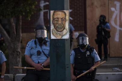 MINNEAPOLIS, MN - MAY 27: A portrait of George Floyd hangs on a street light pole as police officers stand guard at the Third Police Precinct during a face off with a group of protesters on May 27, 2020 in Minneapolis, Minnesota. The station has become the site of an ongoing protest after the police killing of George Floyd. Four Minneapolis police officers have been fired after a video taken by a bystander was posted on social media showing Floyds neck being pinned to the ground by an officer as he repeatedly said, I cant breathe. Floyd was later pronounced dead while in police custody after being transported to Hennepin County Medical Center.   Stephen Maturen/Getty Images/AFP<!-- NICAID(14509757) -->