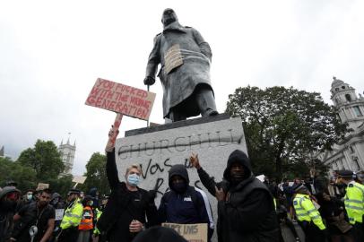 Protesters pose for a photograph in front of the defaced statue of former British prime minister Winston Churchill, with the words (Churchill) was a racist written on its base in Parliament Square, central London after a demonstration outside the US Embassy, on June 7, 2020, organised to show solidarity with the Black Lives Matter movement in the wake of the killing of George Floyd, an unarmed black man who died after a police officer knelt on his neck in Minneapolis. - Taking a knee, banging drums and ignoring social distancing measures, outraged protesters from Sydney to London on Saturday kicked off a weekend of global rallies against racism and police brutality. (Photo by ISABEL INFANTES / AFP)<!-- NICAID(14517461) -->