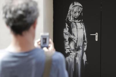  (FILES) In this file photo taken on June 25, 2018 a man takes a photograph of an artwork by street artist Banksy in Paris on a side street to the Bataclan concert hall where a terrorist attack killed 90 people on Novembre 13, 2015. - The stolen Banksy work has been found in Italy, AFP reports on June 10, 2020. (Photo by Thomas SAMSON / AFP) / RESTRICTED TO EDITORIAL USE - MANDATORY MENTION OF THE ARTIST UPON PUBLICATION - TO ILLUSTRATE THE EVENT AS SPECIFIED IN THE CAPTIONEditoria: ACELocal: ParisIndexador: THOMAS SAMSONSecao: policeFonte: AFPFotógrafo: STF<!-- NICAID(14519054) -->