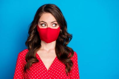 Closeup photo of pretty curly lady closed half face big eyes look side empty space wear dotted red blouse dress protective facial respiratory mask isolated blue color backgroundCloseup photo of pretty curly lady closed half face big eyes look side empty space, wear dotted red blouse dress protective facial respiratory mask isolated blue color backgroundFonte: 351532294<!-- NICAID(14528997) -->