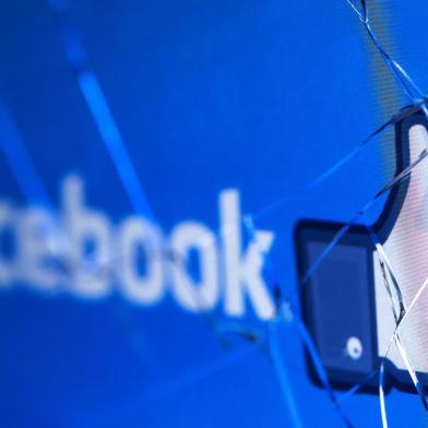 (FILES) In this file photo taken on May 16, 2018 shows the logo of the social network Facebook on a broken screen of a mobile phone. - Facebook said Thursday, November 15, 2018 it was severing ties with a political consultancy that sought to discredit critics of the social networking giant using questionable campaign-style tactics. The California-based company's announcement followed a lengthy New York Times investigation detailing Facebook's struggles with its image as it came under scrutiny for its handling of Russian-led misinformation efforts. Facebook said in a statement that "we ended our contract" with Definers Public Affairs, which specializes in opposition research and, according to the Times, sought to link anti-Facebook efforts to financier George Soros. But Facebook disputed claims that it used the firm in a nefarious way. (Photo by JOEL SAGET / AFP)<!-- NICAID(13834082) -->