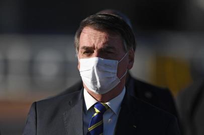 (FILES) In this file photo taken on May 12, 2020, Brazilian President Jair Bolsonaro wears a face mask as he arrives at the flag-raising ceremony before a ministerial meeting at the Alvorada Palace in Brasilia, Brazil, amid the new coronavirus pandemic. - As the number of dead from coronavirus shot up in Brazil, the popularity of far right President Jair Bolosonaro has remained unchanged. (Photo by EVARISTO SA / AFP)<!-- NICAID(14539499) -->