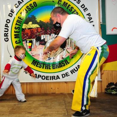  CAXIAS DO SUL, RS, BRASIL, 16/07/2020. Projeto Herdeiros de Palmares ensina capoeira para crianças e adolescentes em vulnerabilidade social no bairro Reolon, em Caxias do Sul. Os voluntários também oferecem refeições para as crianças e suas famílias. Uma vaquinha digital organizada por uma ONG busca recursos para a construção de um refeitório e ampliação da sede, hoje improvisada na casa do criador do projeto. Na foto, Mestre Russo (criador do projeto) com o filho Rafael, 3 anos. (Porthus Junior/Agência RBS)<!-- NICAID(14546417) -->