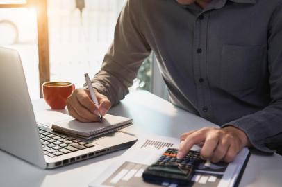  Male businessman working on desk office with using a calculator to calculate the numbers, finance accounting concept.Fonte: 294105357<!-- NICAID(14530970) -->