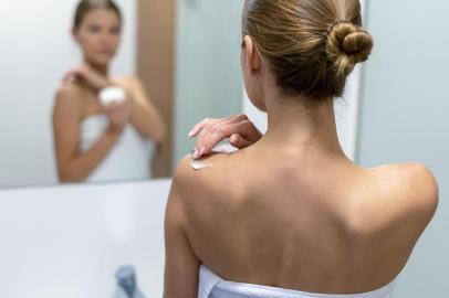 Woman applying body cream on shoulder in bathroomMulher aplicando creme corporal no ombro na casa de banhoIndexador: Oleksandr KondriianenkoFonte: 279854466<!-- NICAID(14325172) -->