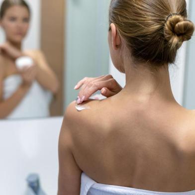 Woman applying body cream on shoulder in bathroomMulher aplicando creme corporal no ombro na casa de banhoIndexador: Oleksandr KondriianenkoFonte: 279854466<!-- NICAID(14325172) -->