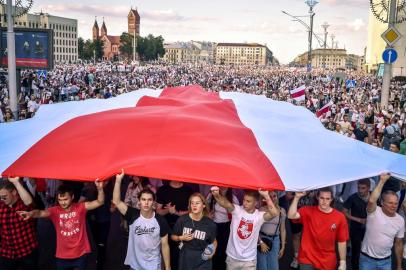  Belarus opposition supporters hold a giant former white-red-white flag of Belarus used in opposition to the government, during a demonstration in central Minsk on August 16, 2020. - The Belarusian strongman, who has ruled his ex-Soviet country with an iron grip since 1994, is under increasing pressure from the streets and abroad over his claim to have won re-election on August 9, with 80 percent of the vote. (Photo by Sergei GAPON / AFP)Editoria: POLLocal: MinskIndexador: SERGEI GAPONSecao: electionFonte: AFPFotógrafo: STR<!-- NICAID(14569180) -->