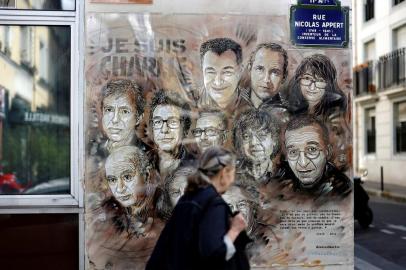 A woman walks past a painting by French street artist and painter Christian Guemy, known as C215, in tribute to members of Charlie Hebdo newspaper who were killed by jihadist gunmen in January 2015, in Paris, on August 31, 2020. - Fourteen alleged accomplices in the 2015 jihadist attacks on the Charlie Hebdo satirical weekly, on a kosher supermarket and in the southern Paris suburb Montrouge go on trial on September 2, more than half-a-decade after days of bloodshed that still shock France. The attacks heralded a wave of Islamist violence that has left 258 people dead and raised unsettling questions about modern Frances ability to preserve security and harmony for a multicultural society. (Photo by THOMAS COEX / AFP) / RESTRICTED TO EDITORIAL USE - MANDATORY MENTION OF THE ARTIST UPON PUBLICATION - TO ILLUSTRATE THE EVENT AS SPECIFIED IN THE CAPTION<!-- NICAID(14580564) -->