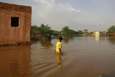 A Sudanese boy wades through a flooded street at the area of al-Qamayir in the capitals twin city of Omdurman, on August 26, 2020. - Sudan on September 5 declared the imposition of a three-month state of emergency nationwide after record-breaking torrential floods caused by more than a month heavy rains left dozens dead and 100,000 damaged properties in their wake, in one of the worst natural disasters in decades, according to state news agency SUNA. (Photo by ASHRAF SHAZLY / AFP)<!-- NICAID(14585491) -->