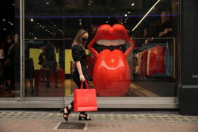 An employee poses wearing a branded facemask walking past the exterior of of The Rolling Stones new flagship store in London on September 8, 2020 during the media preview. - The Rolling Stones new flagship store at 9 Carnaby Street opens on September 9. (Photo by ISABEL INFANTES / AFP)<!-- NICAID(14588432) -->