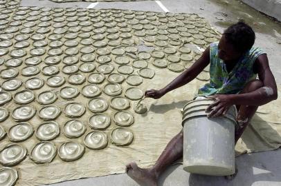 A Haitian woman bakes clay biscuits under the Sun May 9, 2008 in the Port-au-Prince slum of Cite Soleil. As the food crisis continues in Haiti, rice and bean prices have increased by some 100 percent according to officials, forcing many to turn to the clay biscuits as a source of food. The clay is mixed with salt and vegetable fat and dried in the sun.  AFFP PHOTO/Thony BELIZAIRE (Photo by THONY BELIZAIRE / AFP)<!-- NICAID(14586957) -->