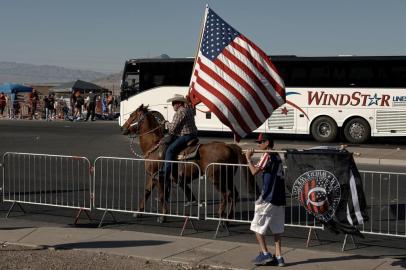  A man rides a horse next to a man holding a QAnon flag, outside the Great American Comeback Event campaign rally with US President Donald Trump at Xtreme Manufacturing in Henderson, Nevada on September 13, 2020. (Photo by Bridget BENNETT / AFP)Editoria: POLLocal: HendersonIndexador: BRIDGET BENNETTSecao: electionFonte: AFPFotógrafo: STR<!-- NICAID(14591657) -->