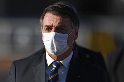 (FILES) In this file photo taken on May 12, 2020, Brazilian President Jair Bolsonaro wears a face mask as he arrives at the flag-raising ceremony before a ministerial meeting at the Alvorada Palace in Brasilia, Brazil, amid the new coronavirus pandemic. - As the number of dead from coronavirus shot up in Brazil, the popularity of far right President Jair Bolosonaro has remained unchanged. (Photo by EVARISTO SA / AFP)<!-- NICAID(14539499) -->