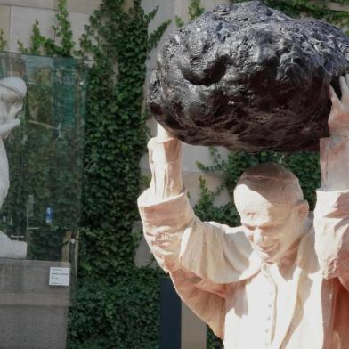 An installation by Polish sculptor Jerzy Kalina entitled Poisoned Source and depicting late Pope John Paul II holding a meteorite over his head stands in a pool of reddish water representing blood, outside the National Museum in Warsaw on September 24, 2020, where the statue was inaugurated. - The work is an artistic response to a controversial statue showing the rock striking down the late pope. (Photo by JANEK SKARZYNSKI / AFP) / RESTRICTED TO EDITORIAL USE - MANDATORY MENTION OF THE ARTIST UPON PUBLICATION - TO ILLUSTRATE THE EVENT AS SPECIFIED IN THE CAPTION<!-- NICAID(14600459) -->