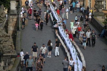  People walk past a half-kilometre long table set up on the Charles Bridge in Prague to celebrate the end of the restrictions linked to the new coronavirus pandemic on June 30, 2020. - Some 2,000 seats are proposed with people being invited to bring and share food. (Photo by Michal Cizek / AFP)Editoria: LIFLocal: PragueIndexador: MICHAL CIZEKSecao: diseaseFonte: AFPFotógrafo: STR<!-- NICAID(14610969) -->