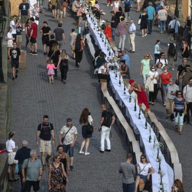  People walk past a half-kilometre long table set up on the Charles Bridge in Prague to celebrate the end of the restrictions linked to the new coronavirus pandemic on June 30, 2020. - Some 2,000 seats are proposed with people being invited to bring and share food. (Photo by Michal Cizek / AFP)Editoria: LIFLocal: PragueIndexador: MICHAL CIZEKSecao: diseaseFonte: AFPFotógrafo: STR<!-- NICAID(14610969) -->