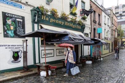 A pedestrian wearing a face mask or covering due to the COVID-19 pandemic, walks past a pub in Dublin on October 19, 2020, amid reports that further lockdown restrictions could be imposed to help mitigate the spread of the novel coronavirus. - Ireland will crank up coronavirus restrictions, prime minister Micheal Martin said last week, announcing a raft of new curbs along the border with the British province of Northern Ireland. (Photo by PAUL FAITH / AFP)<!-- NICAID(14621888) -->