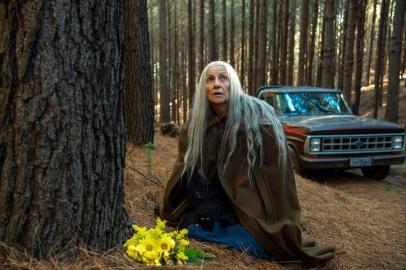 Haia ( Cassia Kis ) leva um ramalhete de flores para a floresta em homenagem a filha. Cena da série Desalma, da Globoplay<!-- NICAID(14621891) -->