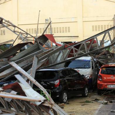 Residents stand next to cars damaged after a gymnasium collapsed at the height of super Typhoon Goni after it hit Tabaco, Albay province, south of Manila on November 1, 2020. - At least seven people were killed as Typhoon Goni pounded the Philippines on November 1, ripping off roofs, toppling power lines and causing flooding in the hardest-hit areas where hundreds of thousands have fled their homes. (Photo by Charism SAYAT / AFP)<!-- NICAID(14631422) -->