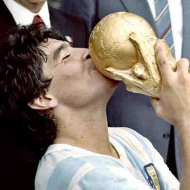 (FILES) In this file picture taken on June 29, 1986 Argentina's football star team captain Diego Maradona kisses the World Soccer Cup won by his team after a 3-2 victory over West Germany at the Azteca stadium in Mexico City watched by Mexican President Miguel de La Madrid (L) and West German Chancellor Helmut Kohl. - Argentine football legend Diego Maradona turns 60 on October 30, 2020. (Photo by STAFF / AFP)<!-- NICAID(14629180) -->