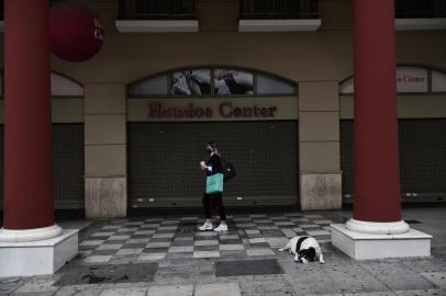 A woman wearing a protective face mask walks next to closed shops in Thessaloniki on November 3, 2020. - Greece announced a two-week lockdown on November 2 on its second largest city of Thessaloniki to try to contain a spike in coronavirus cases. Everything will remain closed, except for schools, and those wanting to leave their homes will have to seek permission via text message. (Photo by Sakis MITROLIDIS / AFP)<!-- NICAID(14635156) -->