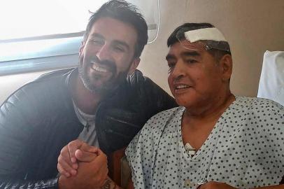  This handout photo released by the press officer of Diego Armando Maradona shows Argentine football legend Diego Maradona (R) shaking hands with his doctor Leopoldo Luque in Olivos, Buenos Aires province, Argentina, on November 11, 2020. - Maradona is expected to leave hospital on Wednesday, eight days after undergoing surgery to remove a blood clot on his brain. Maradona has a signed discharge, and could go home, Leopoldo Luque told reporters outside a clinic in Buenos Aires (Photo by - / Diego Maradona press office / AFP) / RESTRICTED TO EDITORIAL USE - MANDATORY MENTION OF THE ARTIST UPON PUBLICATION - MANDATORY CREDIT AFP PHOTO /DIEGO MARADONA PRESS OFFICE -  TO ILLUSTRATE THE EVENT AS SPECIFIED IN THE CAPTION - NO MARKETING NO ADVERTISING CAMPAIGNS - DISTRIBUTED AS A SERVICE TO CLIENTS - NO ARCHIVE / Editoria: SPOLocal: OlivosIndexador: -Secao: soccerFonte: Diego Maradona press officeFotógrafo: Handout<!-- NICAID(14640976) -->