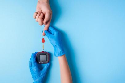 Nurse making a blood test. Man's hand with red blood drop with Blood glucose test strip and Glucose meterNurse making a blood test. . Man's hand with red blood drop with Blood glucose test strip and Glucose meter. Copy space. Top viewFonte: 221451341<!-- NICAID(14641097) -->