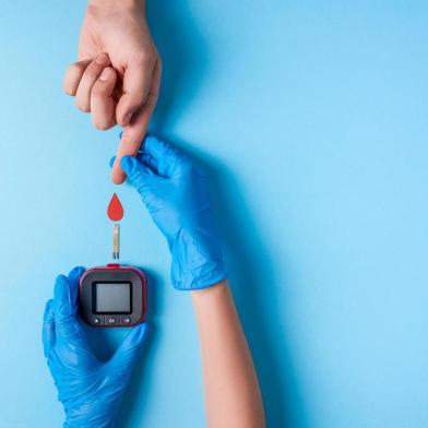 Nurse making a blood test. Man's hand with red blood drop with Blood glucose test strip and Glucose meterNurse making a blood test. . Man's hand with red blood drop with Blood glucose test strip and Glucose meter. Copy space. Top viewFonte: 221451341<!-- NICAID(14641097) -->