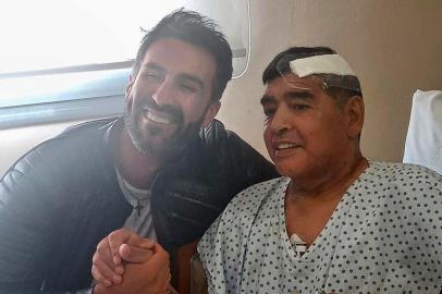  This handout photo released by the press officer of Diego Armando Maradona shows Argentine football legend Diego Maradona (R) shaking hands with his doctor Leopoldo Luque in Olivos, Buenos Aires province, Argentina, on November 11, 2020. - Maradona is expected to leave hospital on Wednesday, eight days after undergoing surgery to remove a blood clot on his brain. Maradona has a signed discharge, and could go home, Leopoldo Luque told reporters outside a clinic in Buenos Aires (Photo by - / Diego Maradona press office / AFP) / RESTRICTED TO EDITORIAL USE - MANDATORY MENTION OF THE ARTIST UPON PUBLICATION - MANDATORY CREDIT AFP PHOTO /DIEGO MARADONA PRESS OFFICE -  TO ILLUSTRATE THE EVENT AS SPECIFIED IN THE CAPTION - NO MARKETING NO ADVERTISING CAMPAIGNS - DISTRIBUTED AS A SERVICE TO CLIENTS - NO ARCHIVE / Editoria: SPOLocal: OlivosIndexador: -Secao: soccerFonte: Diego Maradona press officeFotógrafo: Handout<!-- NICAID(14640976) -->