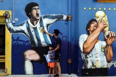  A man and his child pay tribute next to a mural depicting Argentine football legend Diego Maradona at La Boca neighborhood, in Buenos Aires on November 25, 2020, on the day of his death. (Photo by ALEJANDRO PAGNI / AFP)Editoria: SPOLocal: Buenos AiresIndexador: ALEJANDRO PAGNISecao: soccerFonte: AFPFotógrafo: STR<!-- NICAID(14652385) -->