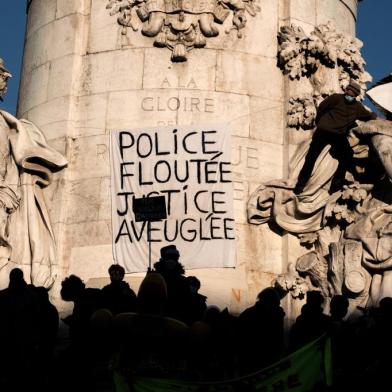 People gather by a banner reading Police, blurring, justice blind and displayed on the statue Le Triomphe de la Republique (The Triumph of the Republic) in the Place de la Republique in Paris on November 28, 2020 during a demonstration to protest against the global security draft law, which Article 24 would criminalise the publication of images of on-duty police officers with the intent of harming their physical or psychological integrity. - Dozens of rallies are planned on November 28 against a new French law that would restrict sharing images of police, only days after the country was shaken by footage showing officers beating and racially abusing a black man. (Photo by JOEL SAGET / AFP)<!-- NICAID(14655346) -->