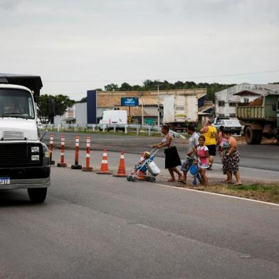  SAPUCAIA DO SUL, RS, BRASIL, 30-11-2020: Kauane Francieli (D) e outras pessoas se arriscam para atravessar a RS-118, com transito intenso, perto da rua Alcebiades Tavares. Obras de duplicacao da RS-118, trecho de 22 quilometros entre a BR-116 e a BR-290, a Freeway, entre Sapucaia do Sul e Gravatai.  (Foto: Mateus Bruxel / Agencia RBS)Indexador: Mateus Bruxel<!-- NICAID(14656776) -->