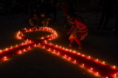 Volunteers light candles forming the shape of a red ribbon during an awareness event on the eve of the World AIDS Day, in Kathmandu on November 30, 2020. (Photo by PRAKASH MATHEMA / AFP)<!-- NICAID(14657468) -->