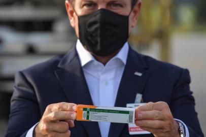  Sao Paulo Governor Joao Doria shows to members of the media a package of the CoronaVac vaccine as containers carrying doses of it are unloaded from a cargo plane that arrived from China at Guarulhos International Airport in Guarulhos, near Sao Paulo, Brazil, on December 03, 2020. - Brazil received this Thursday the second lot with 600 liters of the CoronaVac vaccine, developed by the Chinese laboratory Sinovac Biotech. (Photo by NELSON ALMEIDA / AFP)Editoria: HTHLocal: Sao PauloIndexador: NELSON ALMEIDASecao: diseaseFonte: AFPFotógrafo: STF<!-- NICAID(14659605) -->