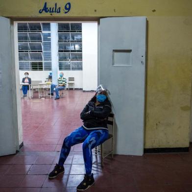 A poll worker sits as she wait for voters to arrive at a polling station in a school in Caracas, on December 6, 2020 during the Venezuelas legislative elections. - Venezuelans voted Sunday in legislative elections set to tighten President Nicolas Maduros grip on power and further weaken his US-backed opposition rival Juan Guaido, who is leading a boycott of the polls he calls a fraud. (Photo by Cristian Hernandez / AFP)