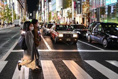 A couple cross a street in Tokyo on December 7, 2020. (Photo by CHARLY TRIBALLEAU / AFP)<!-- NICAID(14662842) -->