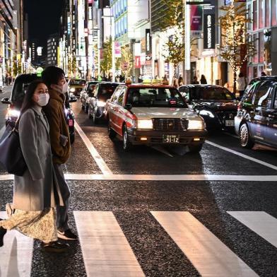 A couple cross a street in Tokyo on December 7, 2020. (Photo by CHARLY TRIBALLEAU / AFP)<!-- NICAID(14662842) -->