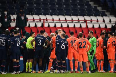  Romanian referee Ovidiu Hategan (in yellow) talks to Istanbul Basaksehirs staff members during the UEFA Champions League group H football match between Paris Saint-Germain (PSG) and Istanbul Basaksehir FK at the Parc des Princes stadium in Paris, on December 8, 2020. - Paris Saint-Germains decisive Champions League game with Istanbul Basaksehir was suspended today in the first half as the players walked off amid allegations of racism by one of the match officials.The row erupted after Basaksehir assistant coach Pierre Webo, the former Cameroon international, was shown a red card during a fierce row on the touchline with staff from the Turkish club appearing to accuse the Romanian fourth official of using a racist term. (Photo by FRANCK FIFE / AFP)Editoria: SPOLocal: ParisIndexador: FRANCK FIFESecao: soccerFonte: AFPFotógrafo: STF<!-- NICAID(14663584) -->