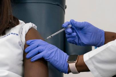  Sandra Lindsay(L), a nurse at Long Island Jewish Medical Center, is inoculated with the Covid-19 vaccine by Dr. Michelle Chester, at Long Island Jewish Medical Center, on December 14, 2020 in the Queens borough of New York. - The rollout of the Pfizer and BioNTech vaccine, the first to be approved by the Food and Drug Administration, ushers in the biggest vaccination effort in US history. More than 299,000 Americans have been killed by the virus, including over 35,000 residents of New York state. (Photo by Mark Lennihan / POOL / AFP)Editoria: HTHLocal: New YorkIndexador: MARK LENNIHANSecao: healthcare policyFonte: POOLFotógrafo: STR<!-- NICAID(14668091) -->