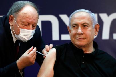 Israeli Prime Minister Benjamin Netanyahu receives a coronavirus vaccine at the Sheba Medical Center, the countrys largest hospital, in Ramat Gan near the coastal city of Tel Aviv, on December 19, 2020. - Netanyahu, 71, and Israels health minister were injected with the Pfizer-BioNTech vaccine live on TV at Sheba Medical Center. Each recipient must receive a booster shot in three weeks for optimal protection from the novel coronavirus. (Photo by AMIR COHEN / POOL / AFP)<!-- NICAID(14673092) -->