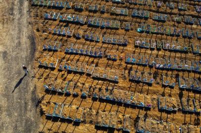  Aerial view showing a man walking past graves in the Nossa Senhora Aparecida cemetery in Manaus on June 21, 2020. - The novel coronavirus has killed at least 464,423 people worldwide since the outbreak began in China last December, being Brazil Latin Americas worsthit country with 49,976 deaths from 1,067,579 cases. (Photo by MICHAEL DANTAS / AFP)Editoria: HTHLocal: ManausIndexador: MICHAEL DANTASSecao: diseaseFonte: AFPFotógrafo: STR<!-- NICAID(14527400) -->