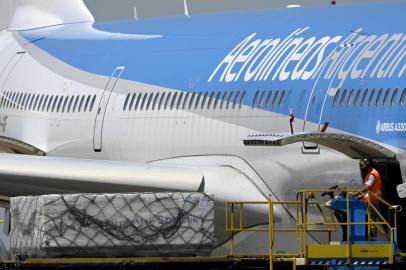 A worker unloads shipping containers with 300,000 doses of the Sputnik V vaccine against COVID-19, at Ezeiza international airport in Buenos Aires outskirts on December 24, 2020. - Argentinas health ministry said Wednesday it has given the controversial Russian Sputnik V coronavirus vaccine emergency authorization, making the country the first in Latin America to do so. (Photo by JUAN MABROMATA / AFP)<!-- NICAID(14676657) -->